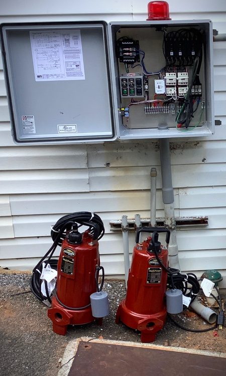 Two red submersible septic pumps with new control panel installation